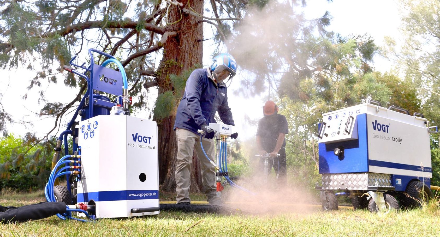 Two Apex operators decompacting soil with VOGT Geo-Injectors, a visible plume of soil released by the pneumatic pulse